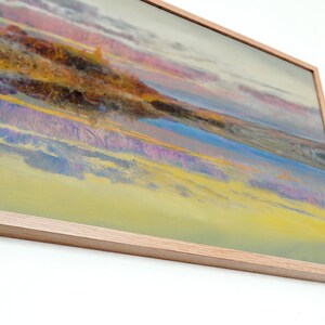 May include: A framed abstract landscape painting with a light wood frame. The artwork features a blend of colors, including yellow, blue, purple, and pink, creating a vibrant and dynamic composition. The painting evokes a sense of a sunset or sunrise over a landscape.