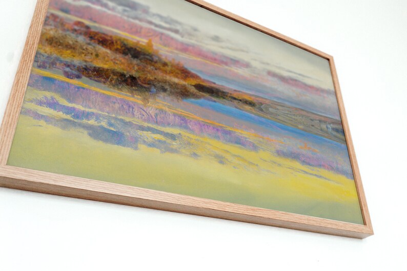 May include: A framed abstract landscape painting with a light wood frame. The artwork features a blend of colors, including yellow, blue, purple, and pink, creating a vibrant and dynamic composition. The painting evokes a sense of a sunset or sunrise over a landscape.