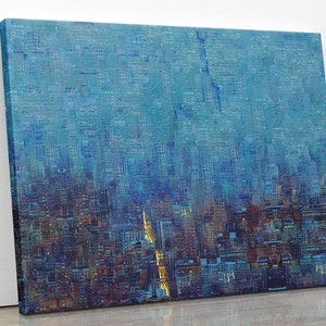May include: Abstract cityscape art print on canvas. The artwork features a textured, layered design in shades of blue, with hints of orange and yellow. The canvas is mounted on a wooden frame, creating a modern aesthetic. The artwork is leaning against a white wall.