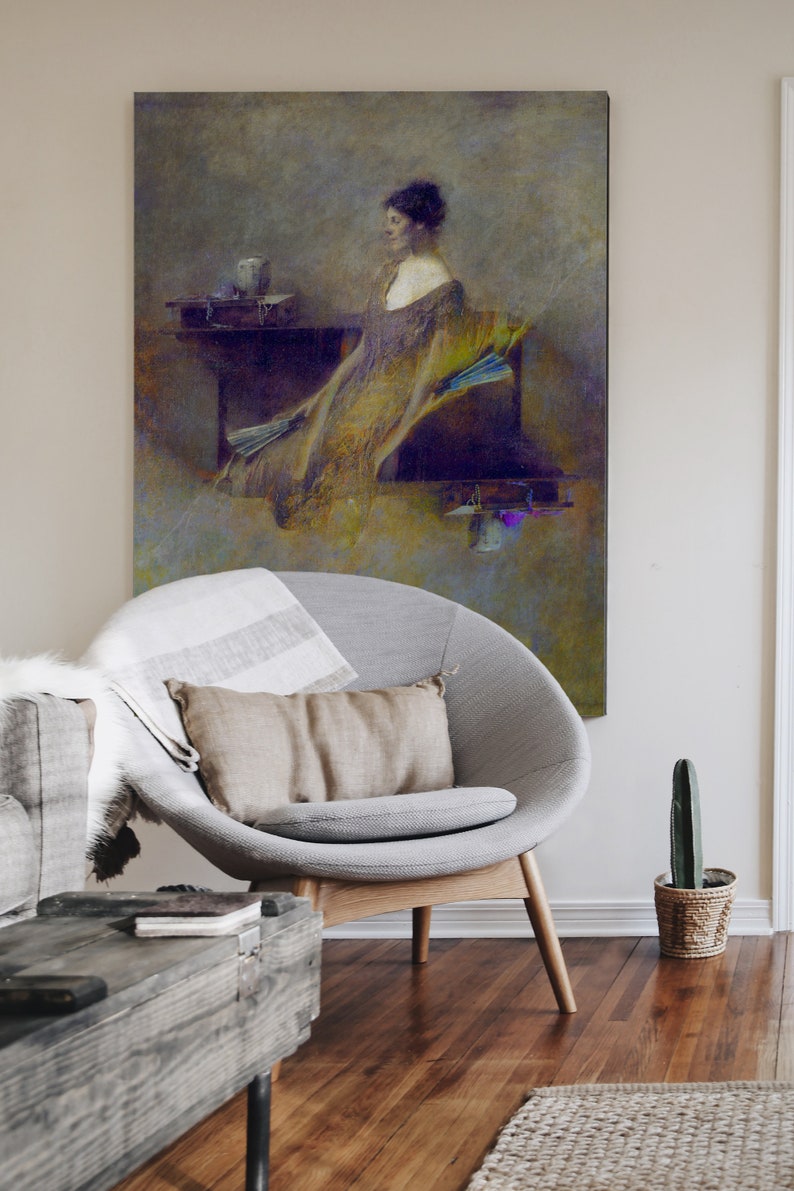 May include: An antique-style painting of a woman in a flowing gown, with a neutral colour palette. The artwork hangs above a modern grey chair with a tan cushion and a striped blanket. A wooden coffee table and a small cactus in a woven pot complete the scene.