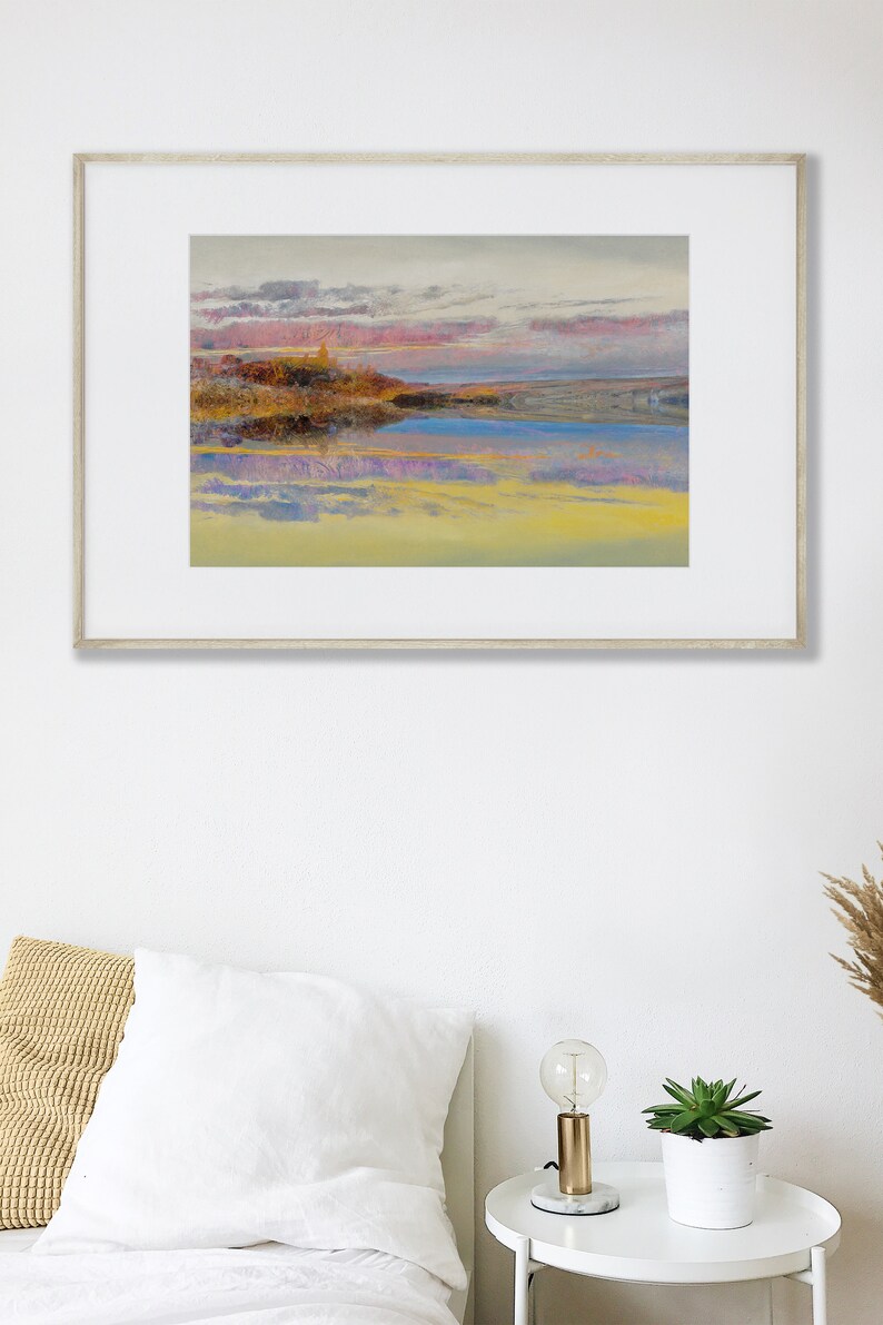 May include: A framed landscape painting with a serene waterscape. The artwork features a colorful sky with pink and gray clouds reflected in the water. The painting is displayed above a bed with white linens.