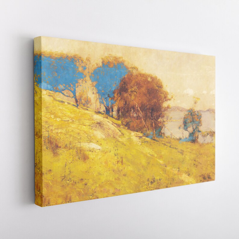 May include: A canvas print of a landscape painting featuring a hillside with yellow grass and trees. The trees have blue and brown foliage. The sky is a pale yellow color, and a body of water is visible in the distance.