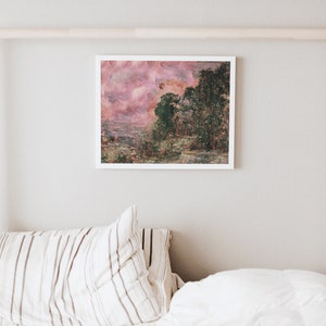 May include: A framed landscape art print featuring a pink and green color palette. The artwork depicts a forest scene with a cloudy sky. The print is displayed on a white wall above a bed with striped pillows and a white comforter.