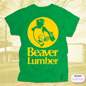 May include: Green t-shirt with a yellow circle featuring a cartoon beaver carrying a log. The text "Beaver Lumber" is printed below the circle.