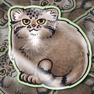Puede incluir: Una pegatina con una ilustración de dibujos animados de un gato de Pallas. El gato tiene un cuerpo redondo, pelaje marrón y ojos amarillos. La pegatina tiene un borde verde claro y un acabado brillante. El gato está sentado con la cola enrollada.