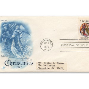 May include: A blue and white Christmas envelope with a stamp featuring a painting of angels playing music. The envelope has a postmark from Washington, D.C. dated November 9, 1972. The text "First Day of Issue" is printed on the envelope.