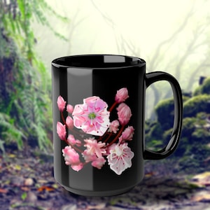 May include: Black ceramic mug with a pink and white floral design. The flowers are in bloom and have a delicate, feminine look.