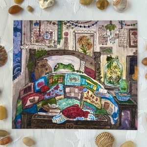 Puede incluir: Ilustración en acuarela de una rana en la cama bajo una colcha de retazos. Un oso de peluche está sentado junto a la rana. Un pez rojo y una pila de libros están al pie de la cama. La habitación está decorada con arte enmarcado y plantas.