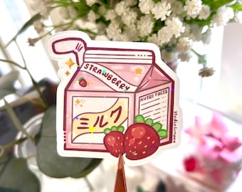 Puede incluir: Una ilustración de dibujos animados rosa y blanca de una caja de leche de fresa. La caja tiene una fresa roja y verde en la parte delantera con las palabras "Leche de fresa" y "Información nutricional".