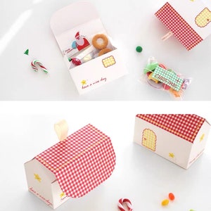 May include: A set of three red and white gingham patterned gift boxes with a white background. The boxes are shaped like houses with a star and the text "have a nice day" on the front. The boxes are filled with small candies and treats.