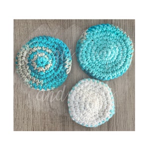 May include: Three crocheted round dishcloths in shades of blue and white. The dishcloths are made with a textured stitch pattern.