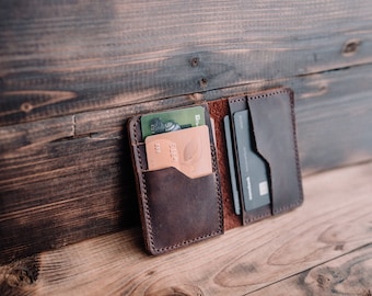 May include: A brown leather wallet with multiple card slots and a flap closure. The wallet is open and has several cards inside, including a green and white card with the word "VISA" on it.