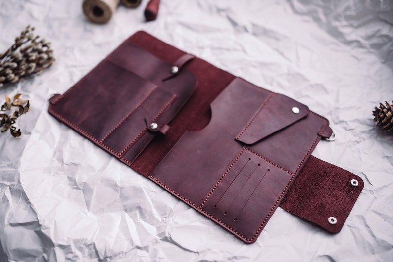 May include: A burgundy leather wallet with multiple compartments and pockets, open to reveal the interior.