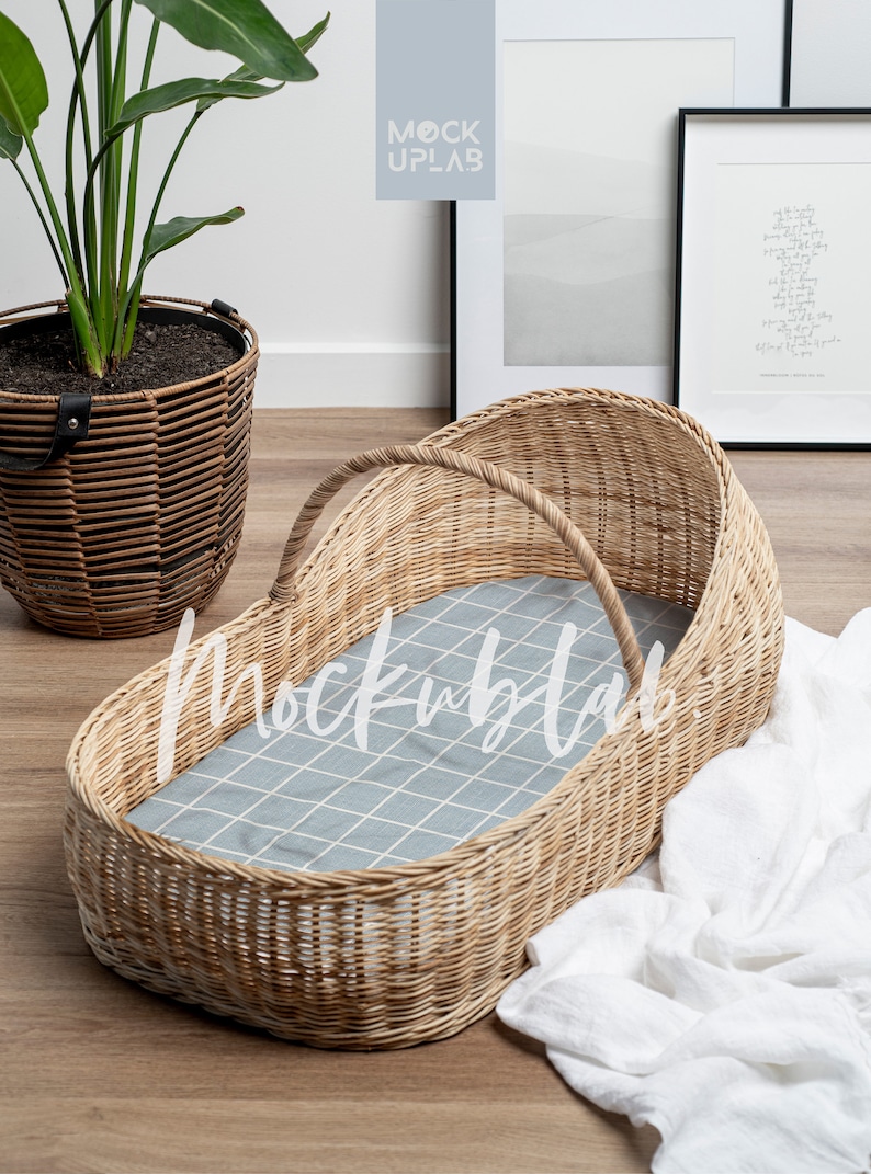 K&ouml;nnte beinhalten: Ein Weidenkorb-Babybett mit einer grauen und wei&szlig;en karierten Innenausstattung. Das Babybett steht auf einem Holzboden mit einer wei&szlig;en Decke in der N&auml;he.