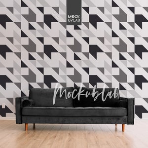 May include: A black velvet sofa with wooden legs sits in front of a wall with a geometric pattern of black, white, and gray triangles. The text "Mockuplab" is visible in the image.