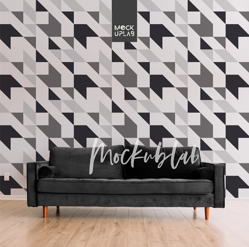 May include: A black velvet sofa with wooden legs sits in front of a wall with a geometric pattern of black, white, and gray triangles. The text "Mockuplab" is visible in the image.