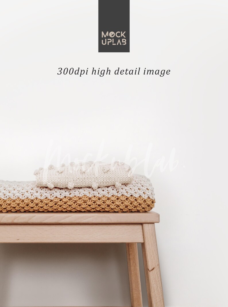 May include: A white knitted blanket with a textured surface sits on top of a yellow knitted blanket. Both blankets are folded and placed on a wooden stool against a white wall.
