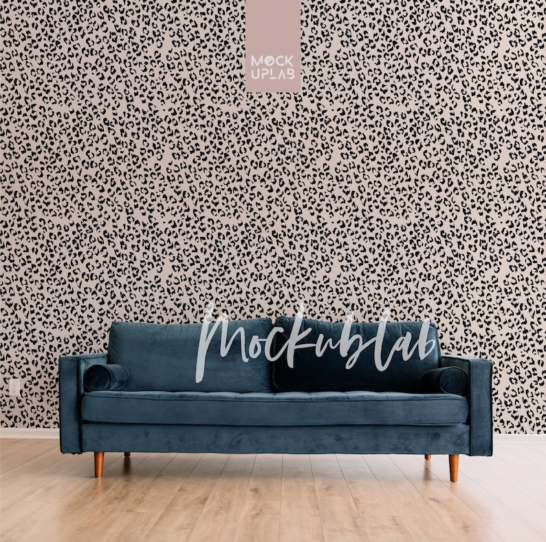 May include: A dark blue velvet sofa with two pillows sits in front of a wall with a black and beige leopard print wallpaper. The sofa has wooden legs.