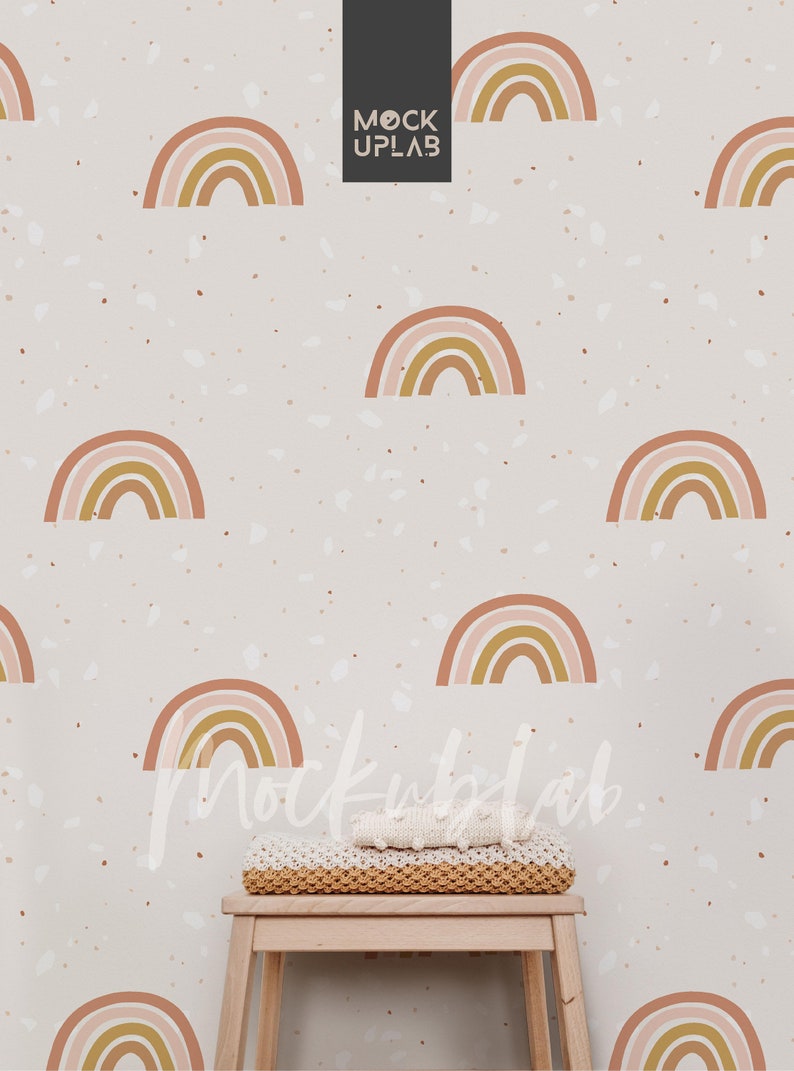 May include: A white wall with a terrazzo pattern featuring a repeating rainbow design. A small wooden stool with a knitted blanket on top sits in front of the wall.