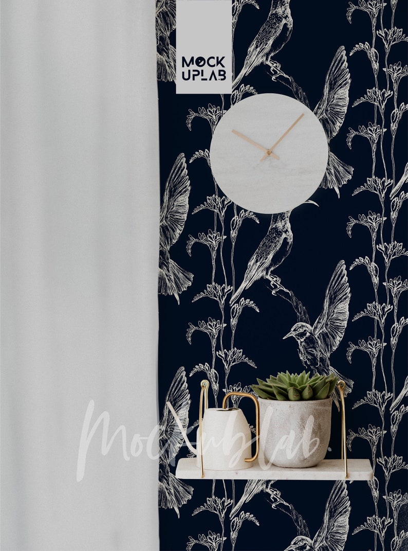 Pu&ograve; includere: Un orologio bianco con lancette nere su uno sfondo blu scuro con un motivo di colibr&igrave; bianchi. L'orologio &egrave; appeso a un muro con uno scaffale bianco sotto. Lo scaffale ha un annaffiatoio bianco e una piccola pianta grassa verde in un vaso bianco.