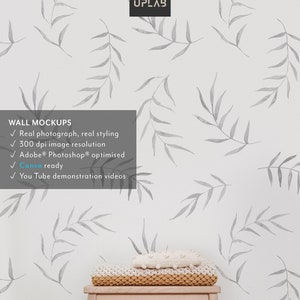May include: A white wall with a gray watercolor leaf pattern. A wooden stool with a knitted throw blanket on top. The text "WALL MOCKUPS" is on the left side of the image. The text "Real photograph, real styling" is below the text "WALL MOCKUPS". The text "300 dpi image resolution" is below the text "Real photograph, real styling". The text "Adobe&reg; Photoshop&reg; optimised" is below the text "300 dpi image resolution". The text "Canva ready" is below the text "Adobe&reg; Photoshop&reg; optimised". The text "You Tube demonstration videos" is below the text "Canva ready". The text "MOCK UPLAB" is in the upper right corner of the image.