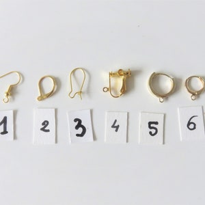 May include: Six different types of earring findings, numbered 1 through 6, on a white background. The findings are all gold-toned metal.