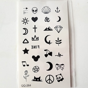 May include: A sheet of temporary tattoos with a variety of black and white designs, including a sun, a heart, a cross, a crown, a star, a crescent moon, a peace sign, a panda, a cat, a rose, a cherry, a musical note, a diamond, a mountain, an anchor, a seashell, an alien, an arrow, an Om symbol, a triangle, a Mickey Mouse head, a bow, a pentagram, and the word "FINE".