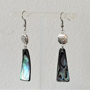 Peut inclure: Une paire de boucles d'oreilles en argent avec un charme rectangulaire en argent et un long pendentif en forme de larme iridescent.