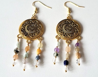 May include: Gold tone earrings with a round, ornate design and dangling strands of colorful beads. The beads are in shades of purple, green, blue, and orange.