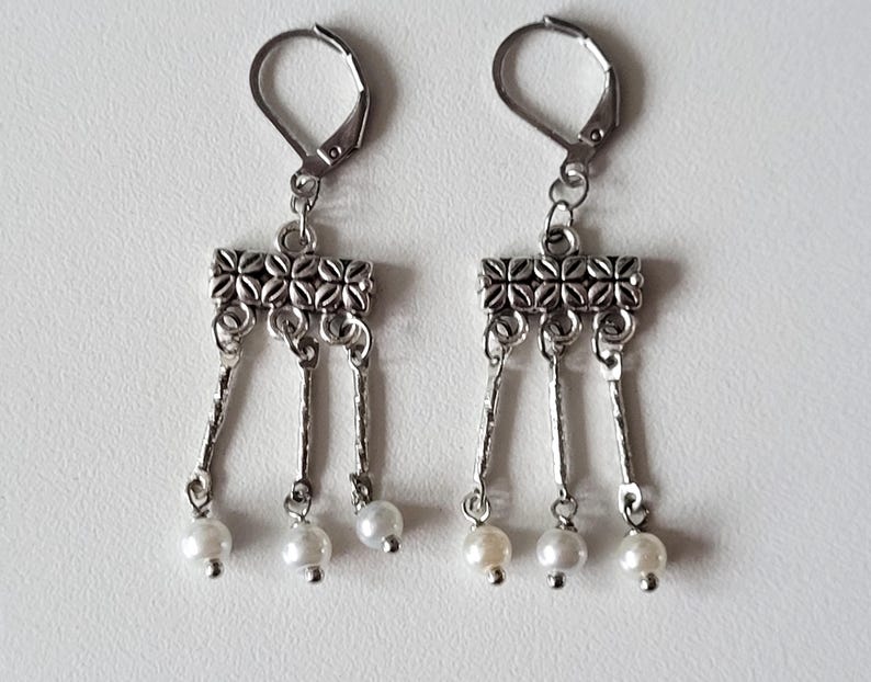 May include: Silver dangle earrings with a decorative silver bar and three white pearl drops.