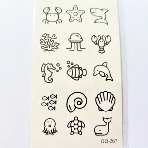 May include: A sheet of temporary tattoos featuring a range of ocean-themed designs, such as a crab, starfish, jellyfish, seahorse, dolphin, seashell, and more. The tattoos are black and white and are arranged in a grid pattern. The sheet is labelled "QQ-267".