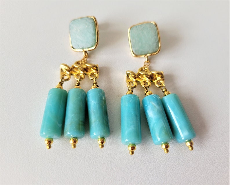 May include: Gold dangle earrings with turquoise blue stone and beads.