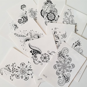 Puede incluir: Diez hojas de tatuaje temporal en blanco y negro con intrincados diseños florales. Las hojas están etiquetadas como HD-01 y HD-02.