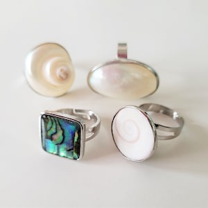Puede incluir: Tres anillos de plata con diferentes incrustaciones de concha. Un anillo tiene una incrustación cuadrada de abulón, otro tiene una incrustación redonda de concha blanca y el último tiene una incrustación redonda de concha blanca con un patrón en espiral.