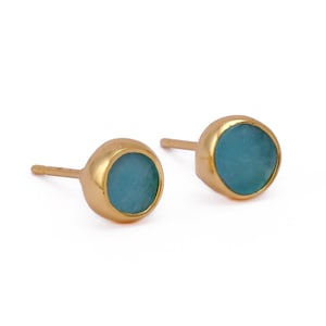 May include: A pair of gold stud earrings with round turquoise blue stones.