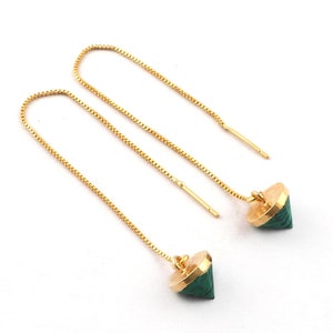 May include: A pair of gold-colored threader earrings with geometric, green malachite-style pendants. The earrings have a delicate chain design and are displayed on a white background. The pendants are cone-shaped with a gold-colored cap.