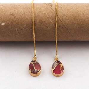 Pode incluir: Um par de brincos de corrente dourada com pedras em forma de gota vermelha e dourada.