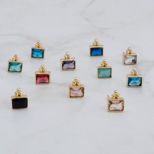 Può includere: Assortimento di 10 orecchini a perno dorati con pietre preziose rettangolari di diversi colori. Le pietre preziose sono nere, blu, rosa, rosse, viola e verdi.