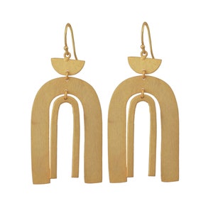 Peut inclure: Boucles d'oreilles dorées avec un design d'arche géométrique. Les boucles d'oreilles sont composées de deux arches, l'une à l'intérieur de l'autre, avec un petit demi-cercle en haut.