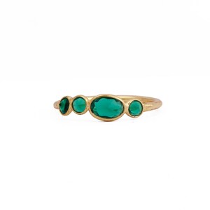 Puede incluir: Un anillo de oro con cinco piedras preciosas de color verde esmeralda. Las piedras son ovaladas y redondas, engastadas en una delicada banda de oro. El anillo es una joya.
