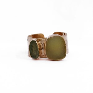 May include: A bronze ring with three green glass stones set into the band. The stones are different shapes and sizes.