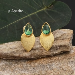 Puede incluir: Pendientes dorados con diseño de hoja. Cada pendiente presenta una gema verde claro en forma de lágrima sobre una hoja dorada texturizada. El texto "9. Apatite" es visible en la imagen.