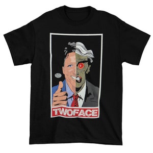 May include: Black t-shirt with a graphic of a man with two faces. One side is a politician, the other side is a villain. The text "TWOFACE" is printed below the graphic.