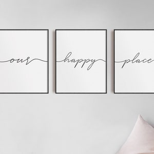 May include: Three black framed prints with white backgrounds. The prints feature the words "our", "happy", and "place" written in a cursive font.