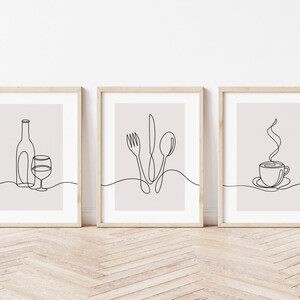 May include: Three minimalist line art prints in wooden frames. The prints depict a wine bottle and glass, a fork, knife, and spoon, and a steaming cup of coffee.
