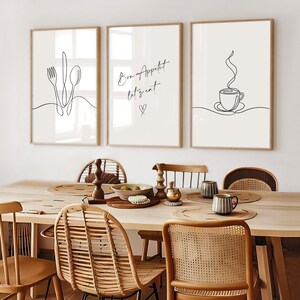 K&ouml;nnte beinhalten: Drei gerahmte Kunstdrucke mit minimalistischen Strichzeichnungen. Einer zeigt Besteck, ein anderer sagt "Bon App&eacute;tit let's eat" mit einem Herz, und der dritte zeigt eine Kaffeetasse. Die Rahmen sind hellbraun.