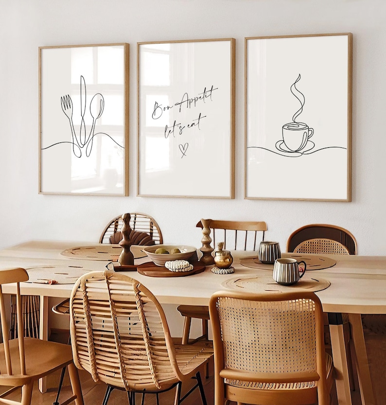 K&ouml;nnte beinhalten: Drei gerahmte Kunstdrucke mit minimalistischen Strichzeichnungen. Einer zeigt Besteck, ein anderer sagt "Bon App&eacute;tit let's eat" mit einem Herz, und der dritte zeigt eine Kaffeetasse. Die Rahmen sind hellbraun.