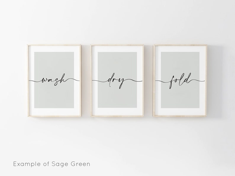 May include: Three framed prints with a sage green background and black calligraphy. The prints read "wash", "dry", and "fold" in a cursive font.