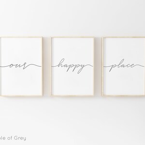 May include: Three framed prints with the words "our", "happy", and "place" written in a cursive font. The prints are hung on a white wall.