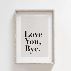 May include: A framed print with a beige background and black text that reads "Love You, Bye."
